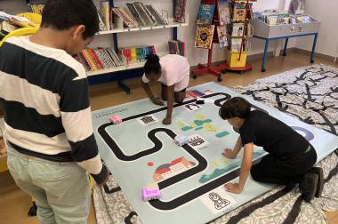 3 élèves supervisent le parcours de Thymio sur le tapis